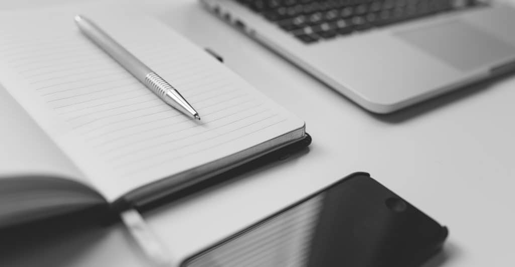 a real estate professional using a pen, paper, smartphone, and computer in his analysis