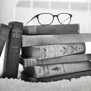 a pile of books with a pair of spectacle atop used as an illustration of tutoring, training, and real estate consulting