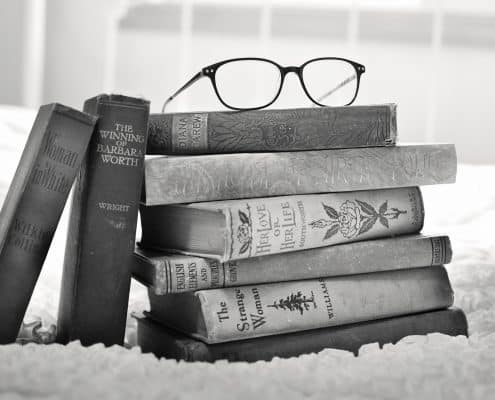 a pile of books with a pair of spectacle atop used as an illustration of tutoring, training, and real estate consulting