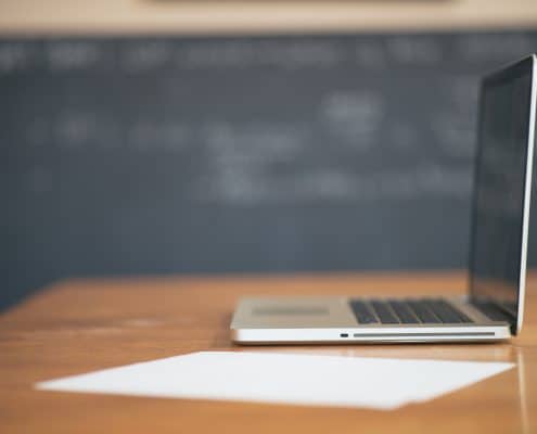 a budding real estate professional prepares his first written resume along side an Apple laptop